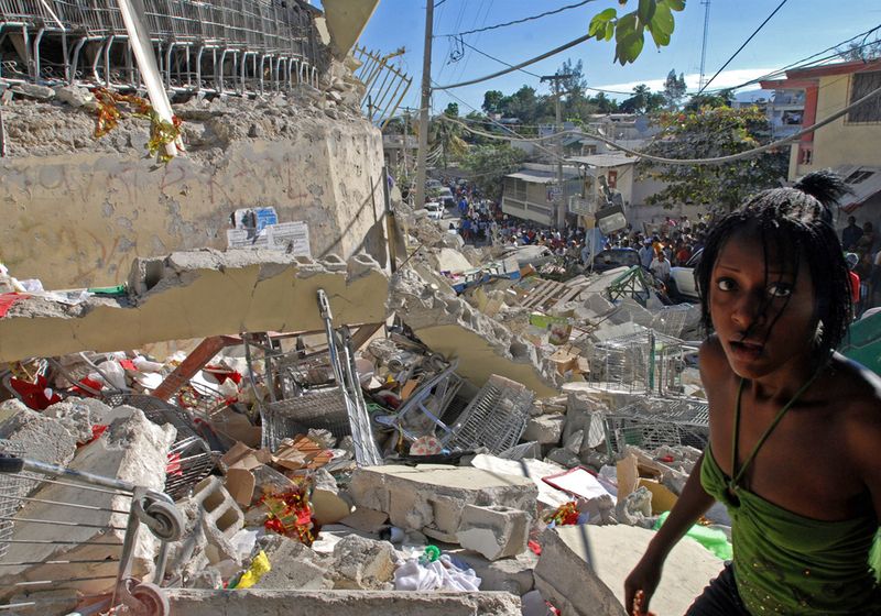 Через день после землетрясения девушка пробирается через обломки супермаркета.