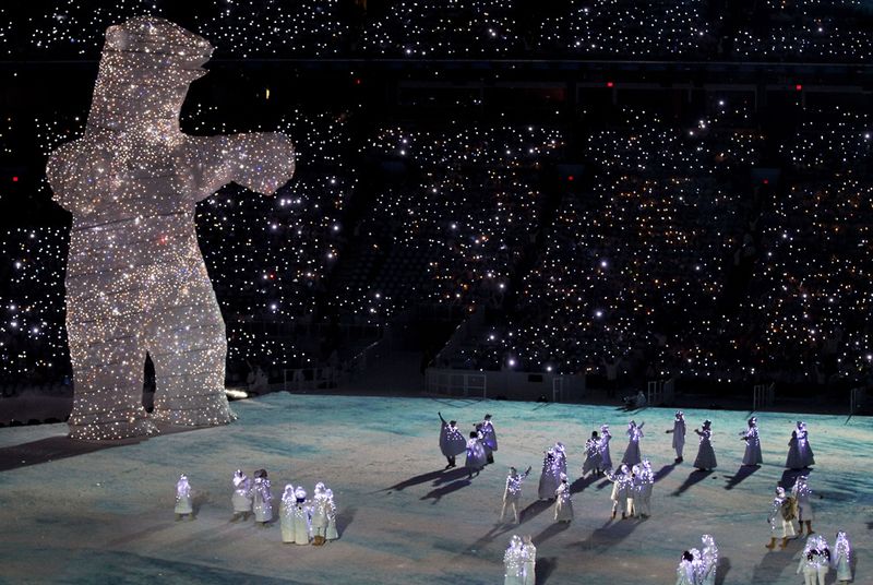 Огромный медведь в светодиодах возвышается над участниками представления на церемонии открытия.
