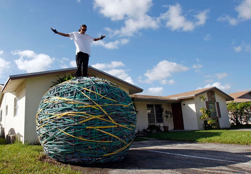 27-летний Джоел Уол стоит на шаре из резинок, который он собрал, у своего дома в Лодерхилле, штат Флорида, 23 октября 2009 года. Джоел, работающий на складе магазина одежды, последние шесть лет отбирал резинки различных размеров и собирал их в аккуратный шар. Книга рекордов Гиннеса назвала этот резиновый шар самым большим в мире в 2008 году.