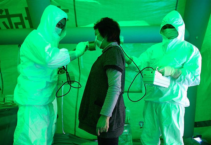 8. Медики в медицинском центре города Хитачи сканируют женщину счетчиками Гейгера, чтобы определить уровень радиационного излучения. Женщину эвакуировали из района в радиусе 20 км от АЭС «Фукусима». Доза радиоактивного облучения этой женщины оказалась не опасной для жизни. (Asahi Shimbun via EPA)