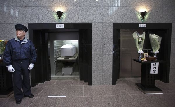 3. Работник крематория готовится закрыть заслон печи, в которую погрузили гроб с телом погибшей во время цунами Катсуко Ойама, 24 марта 2011 года, Курихара, Япония.