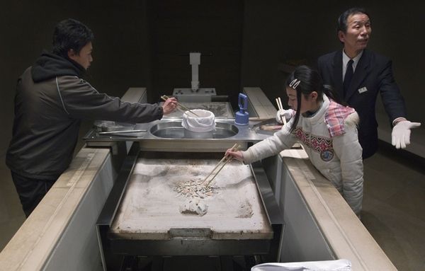 4. Члены семьи и родственники переносят останки Масайши Ойама, погибшего во время цунами, в урну во время церемонии кремации 24 марта 2011 года в Курихара, Япония.