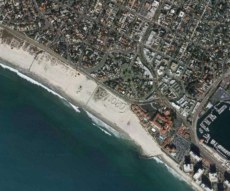 Надпись на пляже в Калифорнии Название пляжа Коронадо-Бич, Калифорния (Сан-Диего) написанно большими камнями, частично покрытыми песком. 