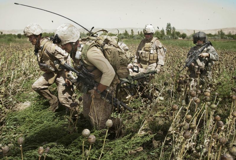 Медик армии США Дэниел Миллер, справа, обеспечивает прикрытие, в то время как американские морские пехотинцы переносят раненного коллегу в санитарный вертолет Целевой группы армии США “Dust Off,” 1-214 авиационного полка в зоне конфликта к северу от Сангин, в провинции Гильменд на юге Афганистана, воскресенье, 13 мая 2011 года.