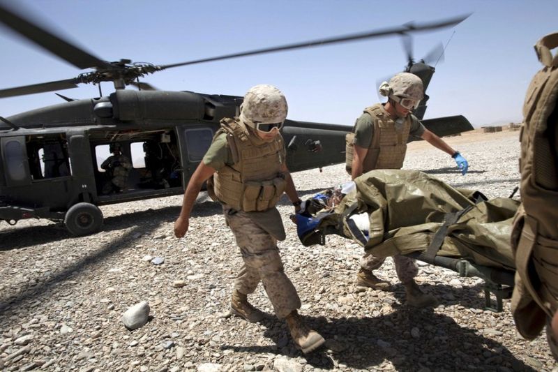  Медики выгружают носилки с раненным солдатом из санитарного вертолета Целевой группы армии США “Dust Off,” 1-214 авиационного полка в провинции Гильменд на юге Афганистана, понедельник, 9 мая 2011 года.