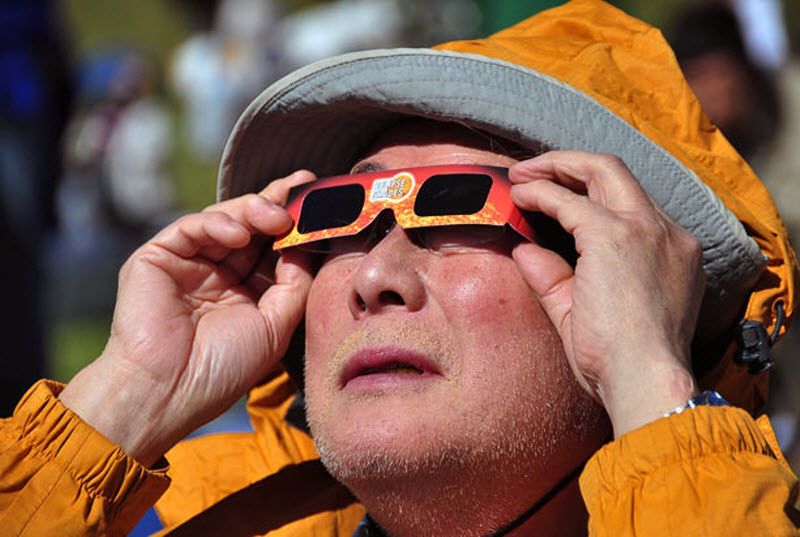 Турист на острове Пасха смотрит солнечное затмение в очках.