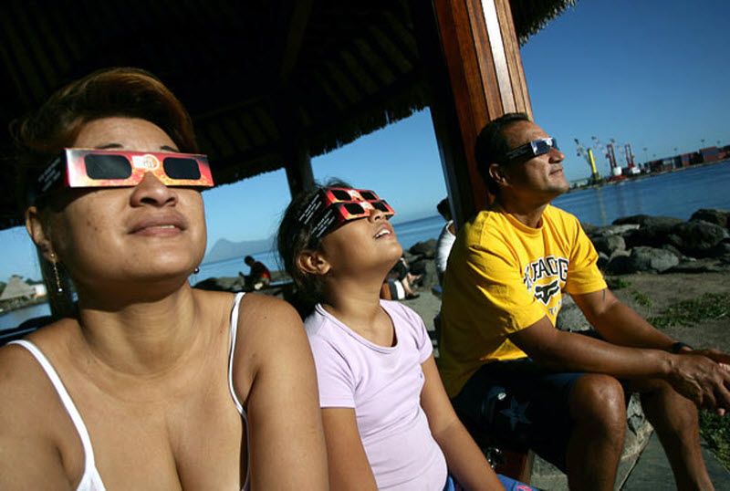 Люди смотрят солнечное затмение в Папите, на острове Таити.