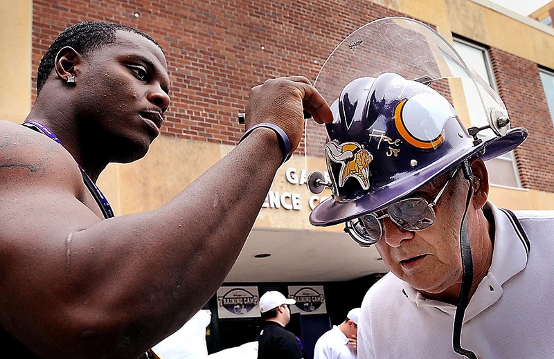Игрок команды по американскому футболу «Minnesota Vikings» подписывает шлем болельщика Милта Торрати в кампусе университета штата Миннесоты в Манкато. (John Cross/Mankato Free Press via Associated Press)