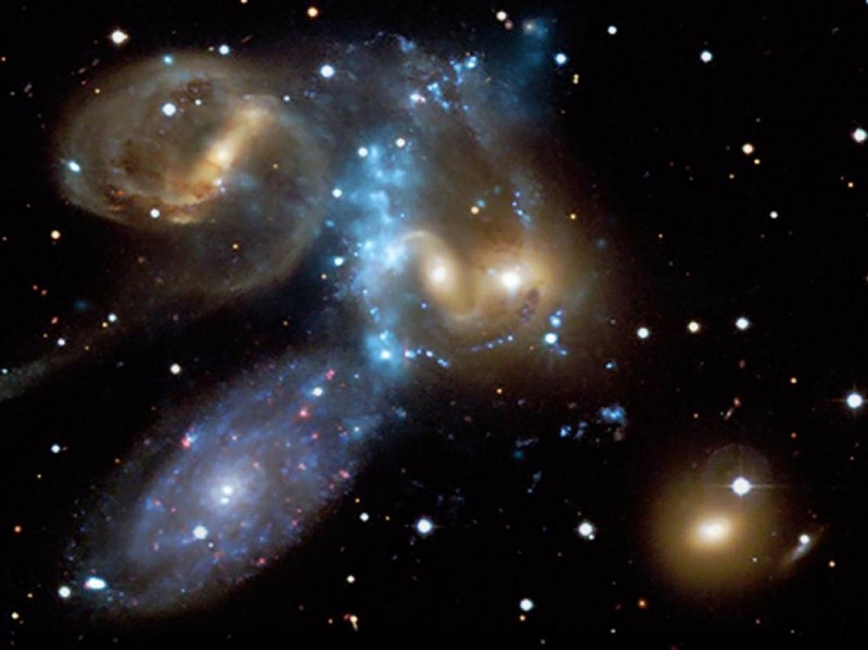 Квинтет Стивена – это компактная группа галактик, открытая около 130 лет назад и расположенная примерно в 280 миллионах световых лет от Земли. Этот снимок, опубликованный 9 июля, сочетает в себе изображение в видимом свете (с помощью телескопа Канада-Франция-Гавайи) и с помощью рентгеновских лучей (из обсерватории Чандра). Голубая полоса в центре изображения представляет собой взрывную волну рентгеновских лучей, возникших из-за крушения галактик. (NASA/CXC/CfA/CFHT)