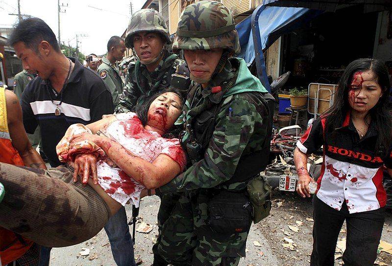 Солдаты несут женщину, раненную в результате взрыва мотоцикла, рядом с магазинами под открытым небом в магазинах Паттани, Таиланд. От целой серии перестрелок, взрывов и военных рейдов за последние два дня на юге Таиланда погибли 11 человек и более 20 получили ранения.