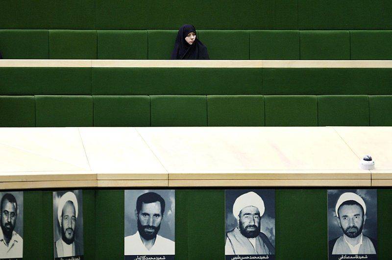 Иранская женщина следит за дебатами во время открытой сессии парламента в Тегеране, темой которой стал предлагаемый президентом Махмудом Ахмадинежадом кабинет министров из 21 члена. (Ниже представлены фотографии ныне действующих парламентариев). Некоторые парламентарии считают, что кандидаты не имеют необходимой квалификации и были выбраны исключительно из-за своей лояльности Ахмадинежаду.