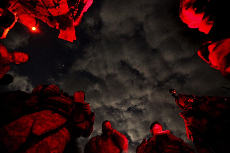 Красная ночная подсветка освещает солдат из Форт-Ричардсон, штат Аляска, во время их подготовки к патрулированию в афганской провинции Хост.