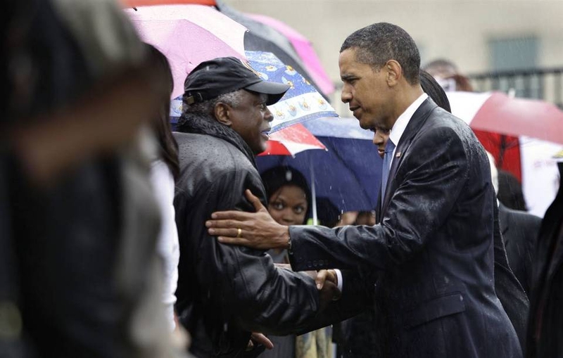 Президент США Барак Обама и первая леди Мишель Обама под проливным дождем приветствуют родственников погибших в Пентагоне во время атак 11-го сентября, после церемонии возложения венков у здания 11 сентября.