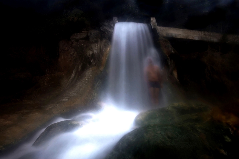 Купальщик стоит под горячим водопадом в греческом спа-комплексе. Именно в этом месте, которое носит название 
