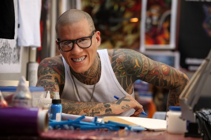 Бразильский татуировщик прервался, делая набросок татуировки в день открытия пятого фестиваля тату в Лондоне.