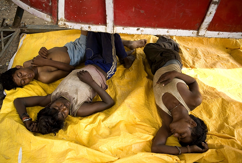 Продавцы спят под деревянными качелями на обочине в Аллахабаде, Индия.
