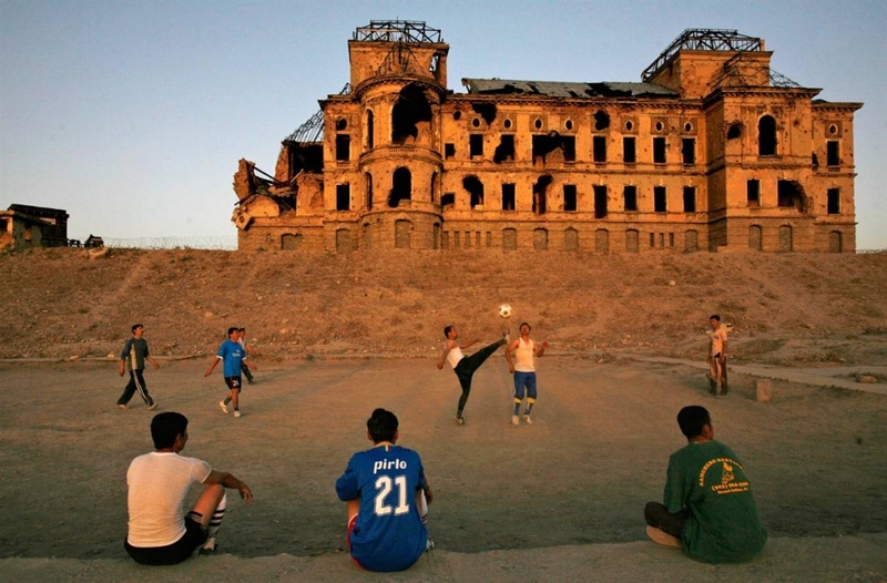 Афганцы играют в футбол перед разбомбленным старым королевским дворцом в Кабуле 23 сентября. Дворец был разработан французским архитектором и построен в 1923 году королем Амануллой.