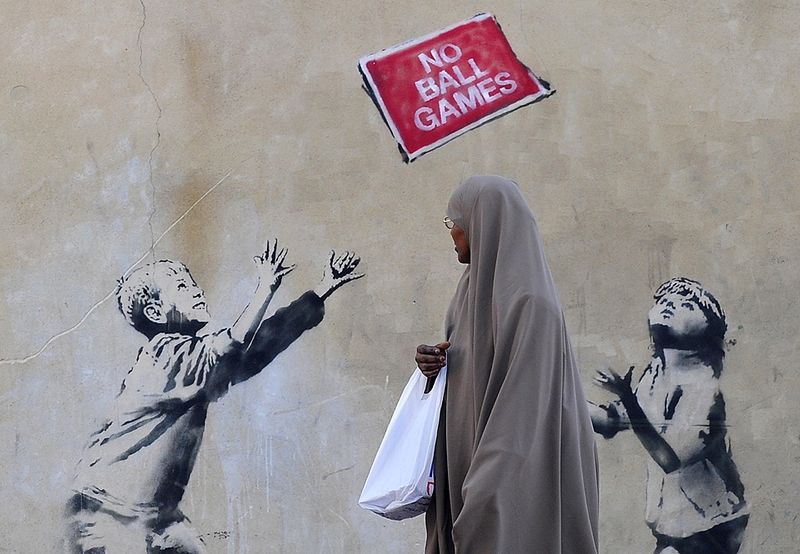 Женщина проходит мимо граффити в Северном Лондоне. Британские СМИ приписывают эту работу уличному художнику известному как Бэнкси.