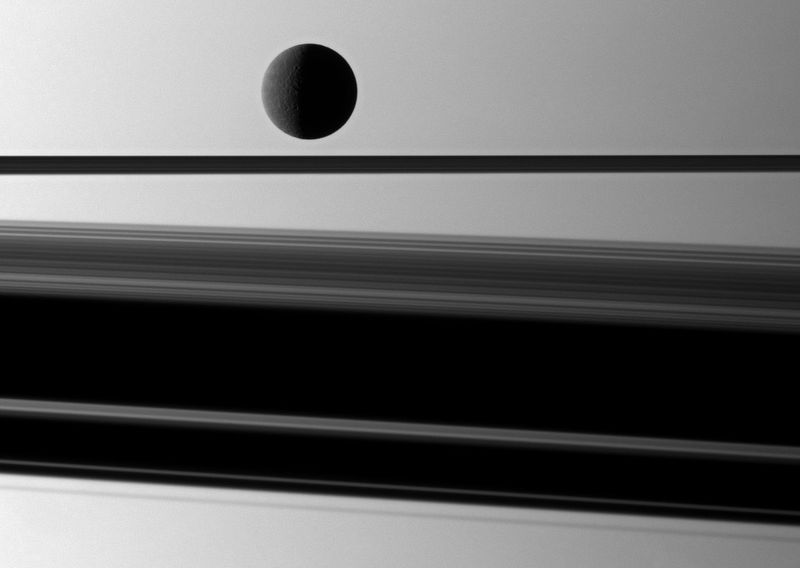 Спутник Сатурна Рея (1528 км) слегка подсвечивается перед планетой с широкой тенью, которую отбрасывают кольца Сатурна, 8 мая. (NASA/JPL/Space Science Institute)