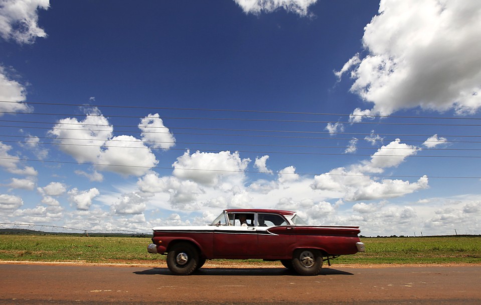 Автомобиль проезжает мимо государственных земель недалеко от города Кивикан, Куба. На Кубе около 250 000 крестьянских семей и 1100 частных предприятий, которые совместно производят около 70% продовольствия в стране.