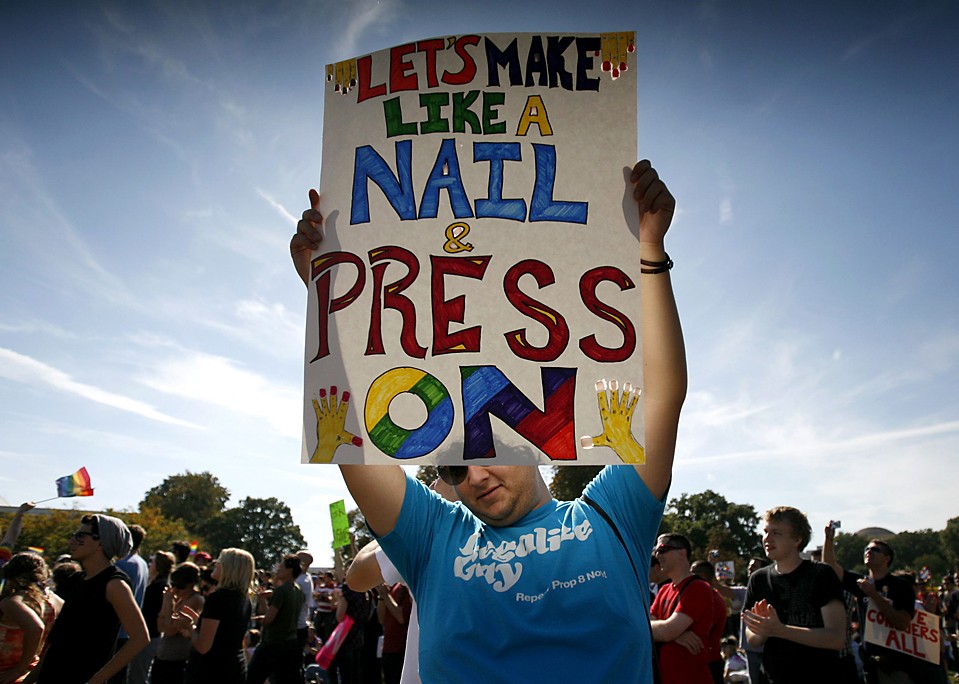 Мужчина держит плакат на митинге активистов выступающих за права геев, который прошел в Вашингтоне в воскресенье. В воздухе развивались тысячи радужных флагов, когда митингующие обратились с призывом к Бараку Обаме, чтобы тот сдержал обещание позволить геям служить в армии. «Эй, Обама, позволь мамочке жениться на мамочке», - скандировали люди