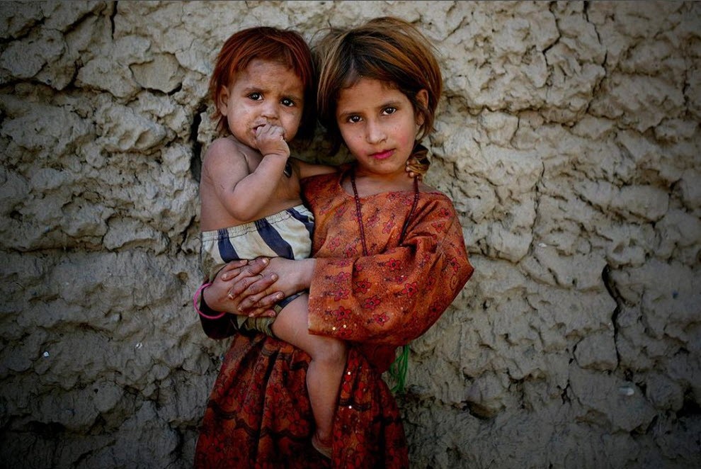 Зубайда, афганская девочка, держит свою младшую сестренку, позируя фотографу в Джелалабаде, провинция Нангархар, к востоку от Кабула.