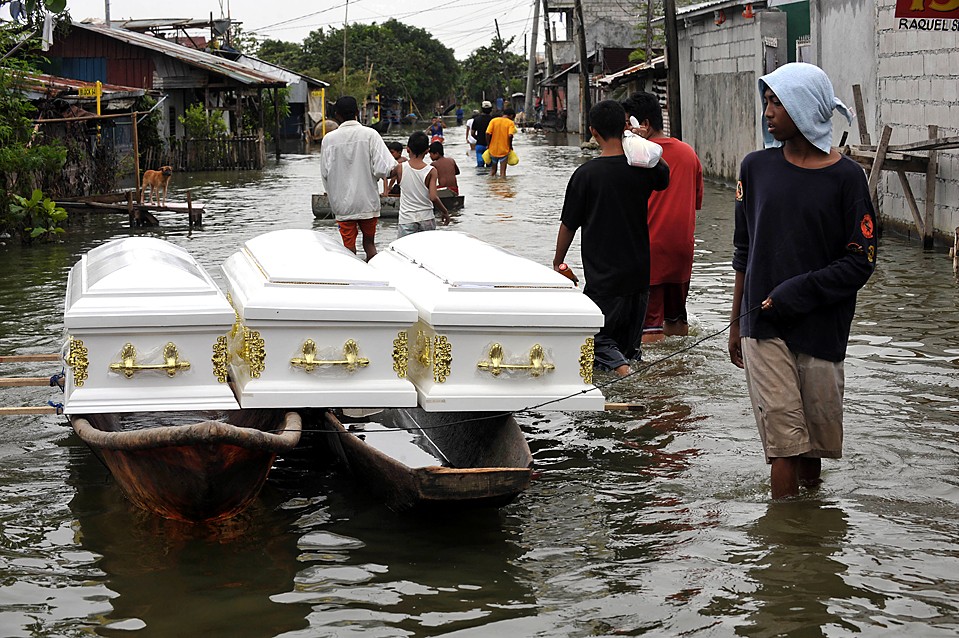 Три пустых деревянных гроба плывут по улице Манилы. Шесть человек погибло в оползнях на северных Филиппинах во время тропического шторма Парма; в прошлом месяце этот же район пострадал от тайфуна Кетсана.