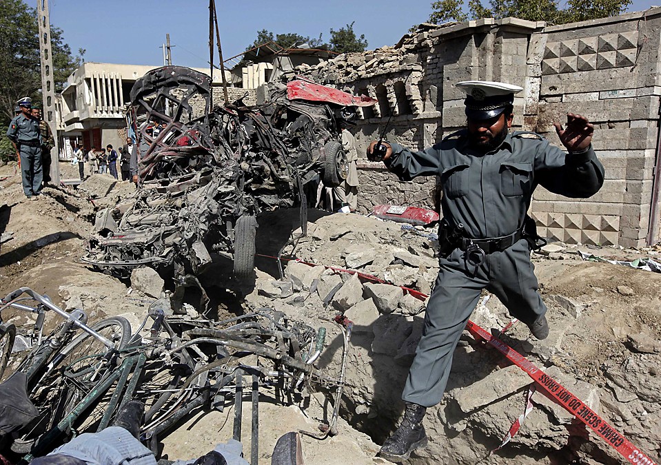 Офицер афганской полиции перепрыгивает через обломки на месте взрыва у здания индийского посольства в Кабуле, Афганистан. Во взрыве автомобиля обвинили боевиков организации «Талибан». В результате взрыва погибло 17 человек.