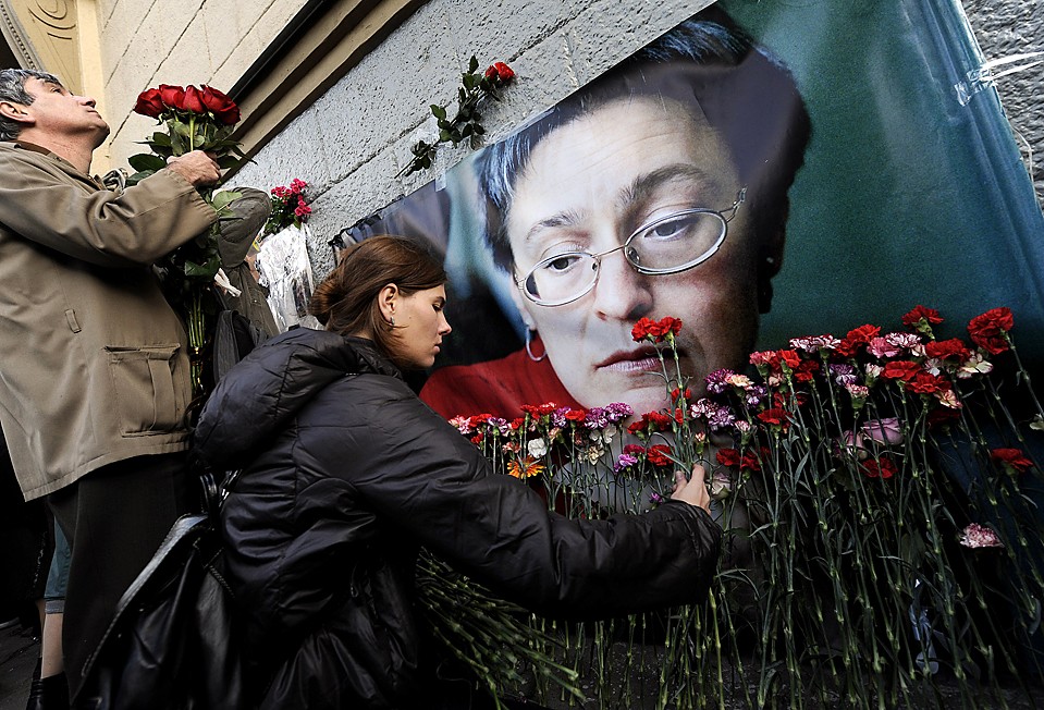 Люди кладут цветы рядом с портретом убитой журналистки Анны Политковской в Москве. Сотни людей собрались во время третьей годовщины ее гибели, призывая власти найти убийц журналистки