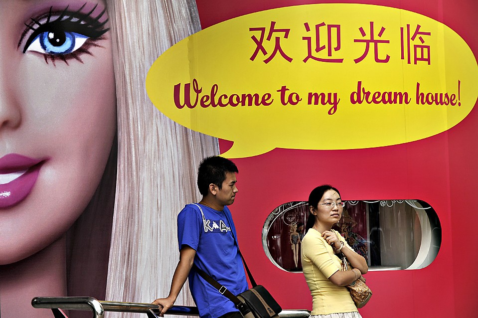 Парень и девушка стоят перед изображением куклы Барби в Шанхае
