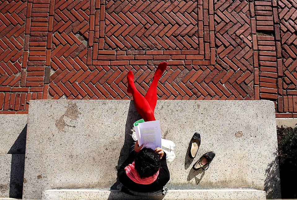 Студентка читает, сидя на пороге у главного кампуса Колумбийского университета в Нью-Йорке