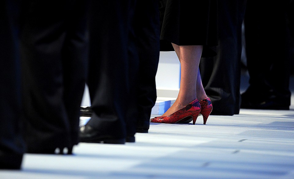 Государственный секретарь по вопросам труда и пенсий Тереза Май стоит на красных каблуках среди своих коллег-мужчин на конференции Консервативной партии в Манчестере, Англия