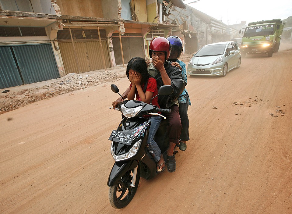 Семья едет по пыльной улице в Паданге, Индонезия. На прошлой неделе тут произошло землетрясение силой в 7,6-баллов, из-за которого погибли более 700 человек