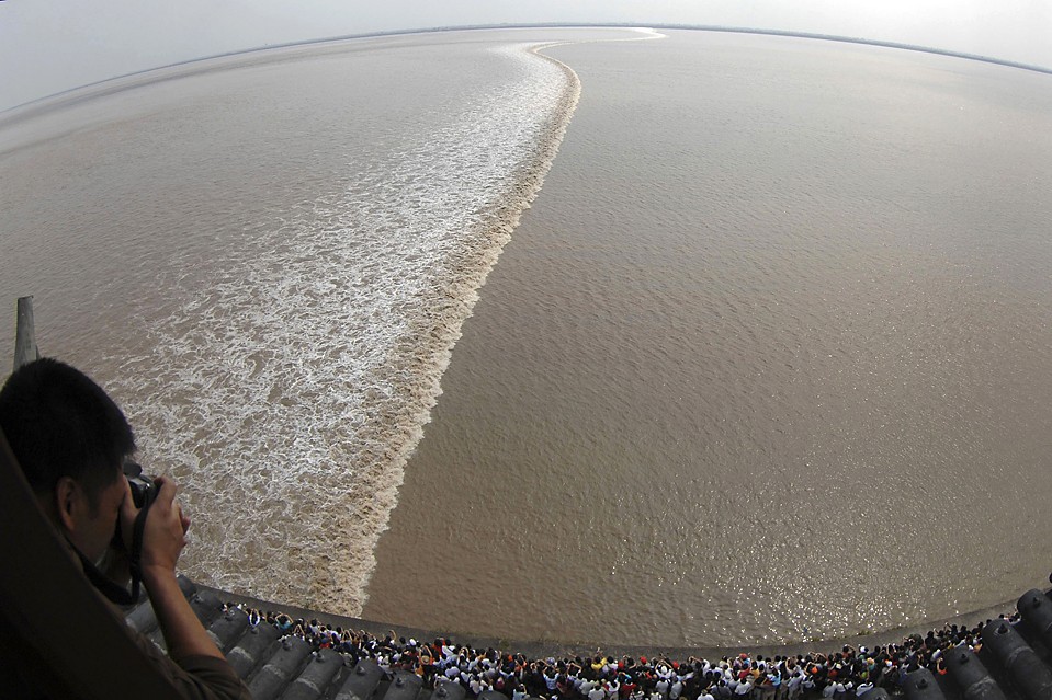 Люди смотрят на волну, стоя над рекой Цяньтан в Haining, провинция Чжэцзян, Китай