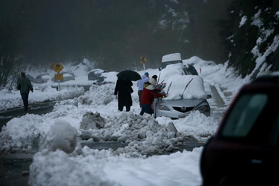 Водители возвращаются к своим автомобилям во время сильного снегопада около Napier в районе Хокс-Бей, в Новой Зеландии. Из-за сильнейшей метели сотни людей не могли вернуться домой.