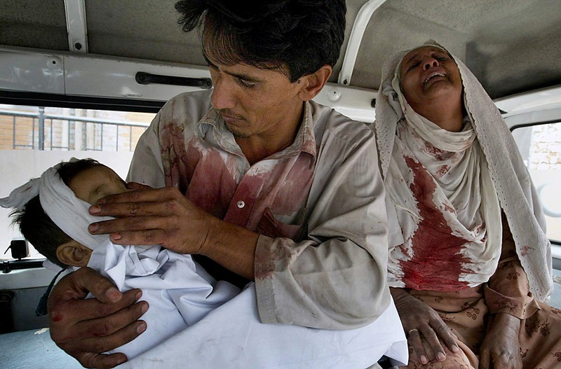 Мужчина держит своего сына, который был убит в результате теракта, а рядом рыдает бабушка мальчика. Снимок сделан внутри фургона одной из больниц в Пешаваре, Пакистан, в воскресенье. Террорист-смертник взорвал себя на рынке, в результате чего был убит выступающий против талибов городской председатель и, по меньшей мере, еще 11 человек.