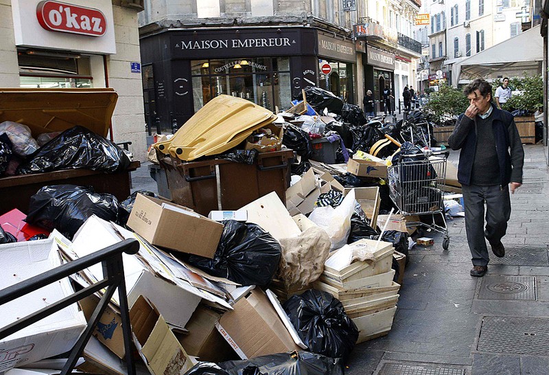 Человек проходит мимо кучи мусора в Марселе, на юге Франции на седьмой день забастовки сборщиков мусора в городе. Одна из компаний, продающая футболки оптом, выпустила в продажу майки и футболки с надписью «Мусор не пройдет!»
