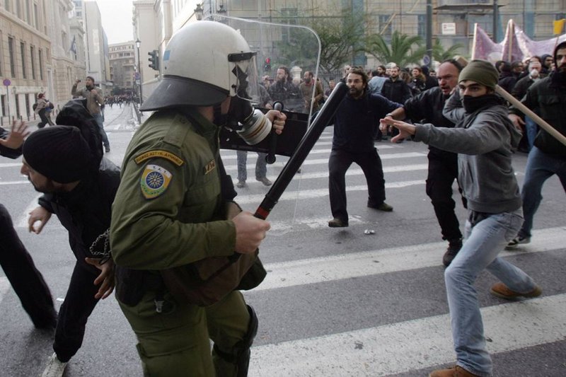 Полицейские и протестующие во время стычки на улице в центре греческой столицы. Демонстранты разбили витрины более чем 20 магазинов на нескольких центральных улицах Афин.