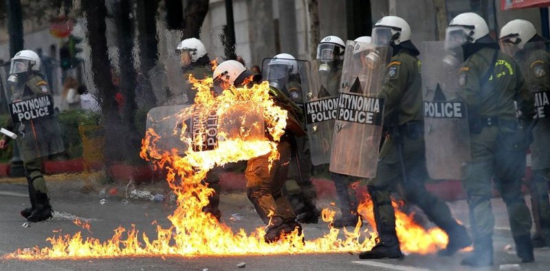 Одежда на одном из полицейских загорелась после того, как демонстранты забросали полицейских бутылками с зажигательной смесью на во время уличных беспорядков в Афинах. Столкновения произошли также во втором по величине греческом городе, Салониках.
