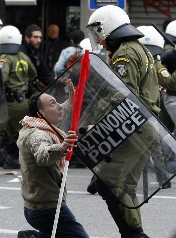 Протестующий стоит на коленях перед сотрудником ОМОНа в Афинах.