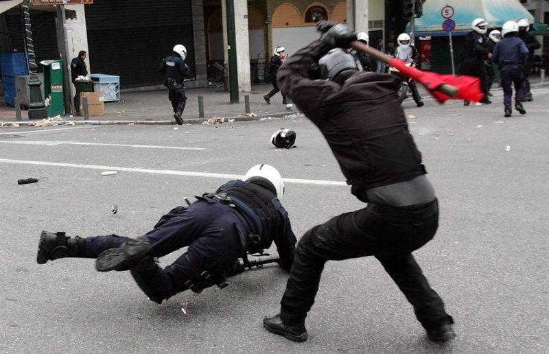 Участник студенческих беспорядков избивает полицейского.