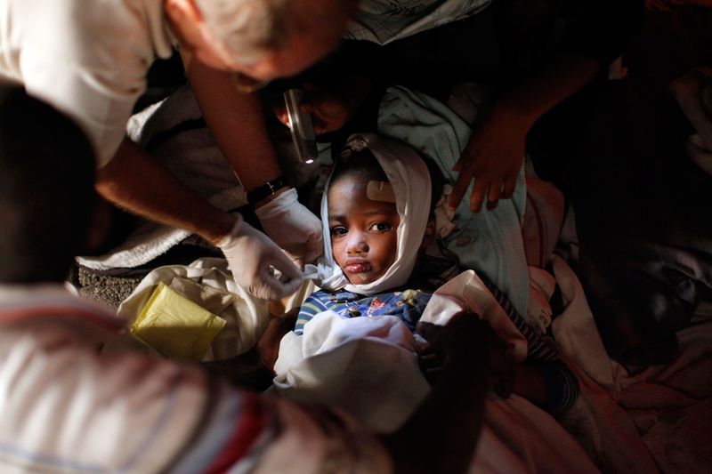 Медики помогают раненому ребенку после землетрясения в Порт-о-Пренс 13 января. 