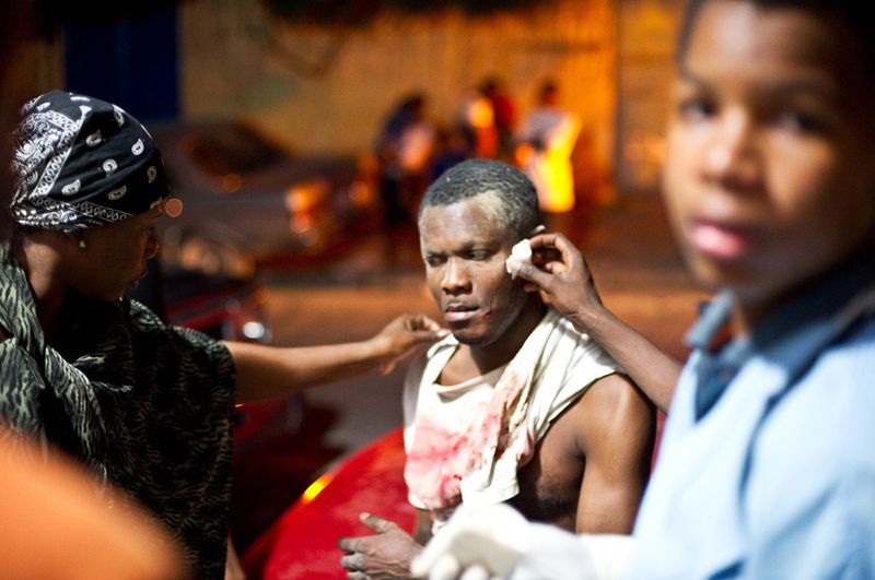 Люди приходят на помощь раненому человеку после землетрясения в Порт-о-Пренс 12 января.