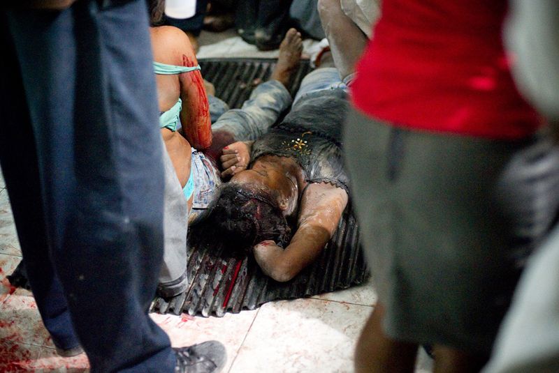 Раненые женщины лежат на полу больницы в ожидании медиков в Петионвилле 12 января в Порт-о-Пренс
