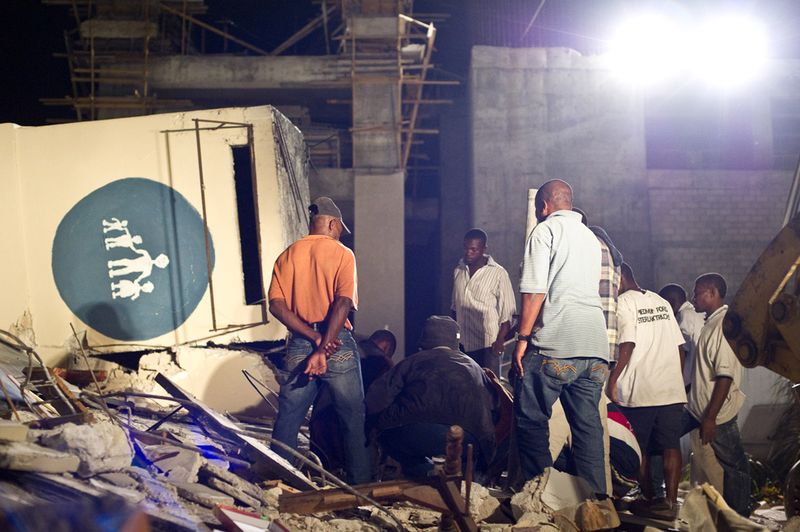 Люди ищут выживших среди руин детской больницы после землетрясения 13 января в Порт-о-Пренс.
