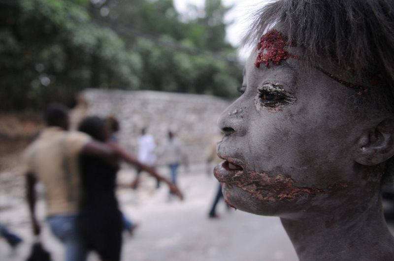 Раненая женщина на улице после землетрясения в Порт-о-Пренс 12 января.
