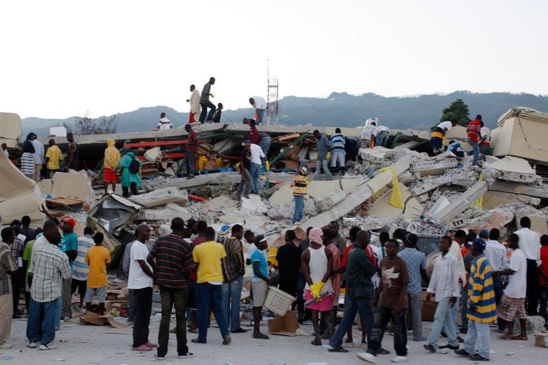 Местные жители в поисках выживших среди обломков рухнувших зданий в Порт-о-Пренс 13 января 2010 года.