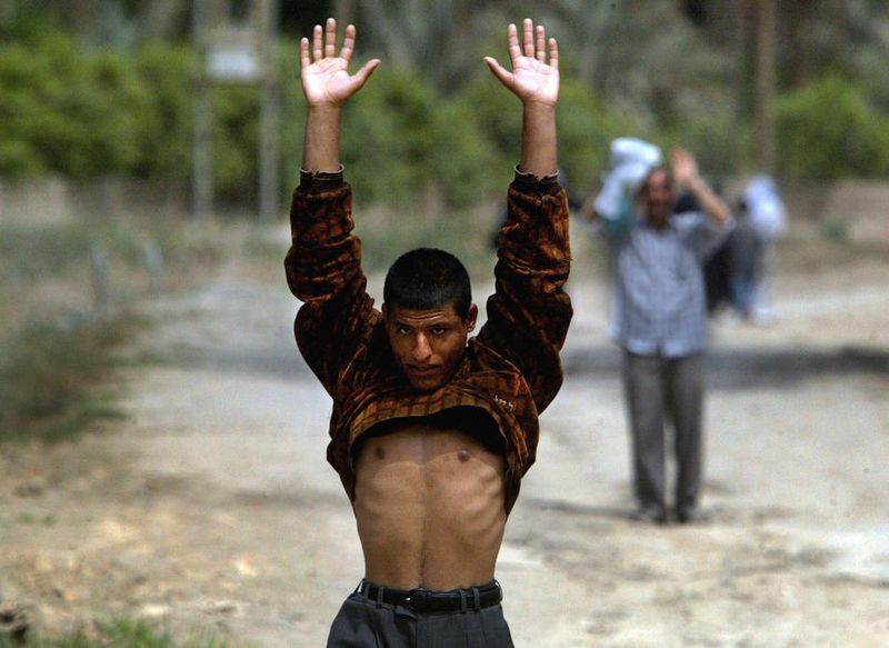 4 апреля 2003 г. При приближении к блокпосту житель Карбалы поднимает рубашку, чтобы показать что он не прячет оружие. 