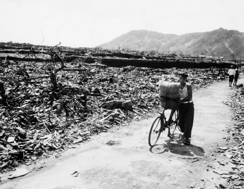 Мужчина с нагруженным велосипедом на расчищенной от руин дороге в Нагасаки 13 сентября 1945 года, спустя месяц после взрыва атомной бомбы.