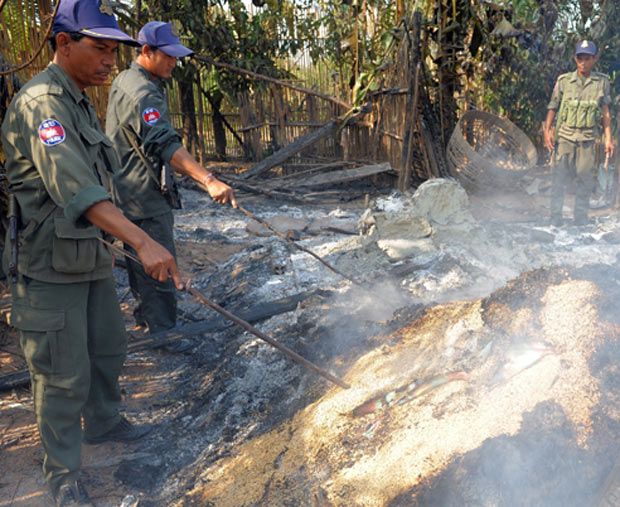  Камбоджийские полицейские изучают развалины дома, сгоревшего после бомбежки деревни неподалеку от границы, провинция Оддар Минчи.
